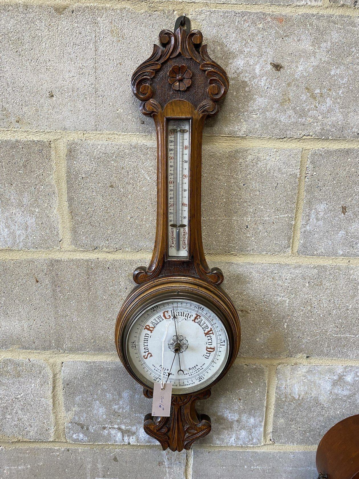 An Edwardian inlaid mahogany tear drop mantel clock, height 34cm and a carved oak aneroid wheel barometer, height 86cm *Please note the sale commences at 9am.
